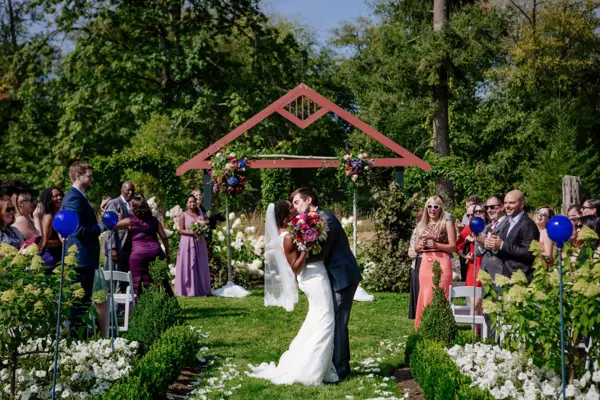 Bride and groom kissing under floral arch at outdoor Pacific Northwest wedding ceremony. Lovely Events.
